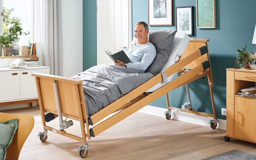 Lesen im Pflegebett der Dali-Serie mit hochgestellter Rückenlehne und hochgelagerten Beinen